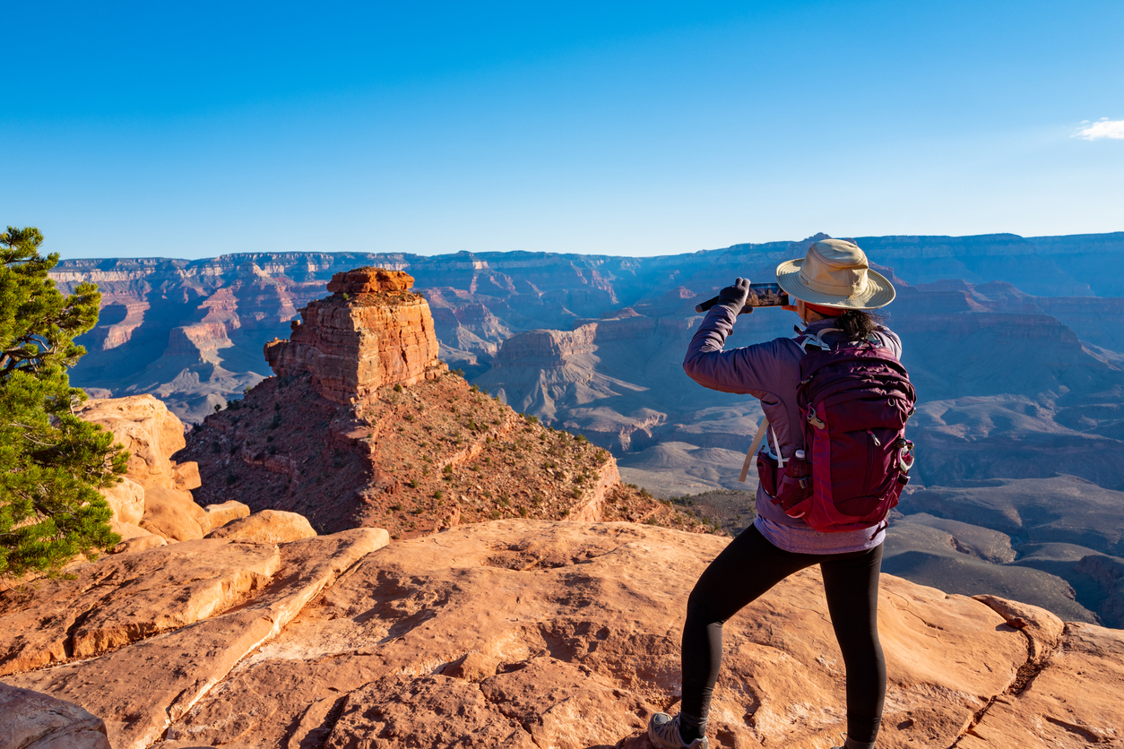 A woman standing on the edge of the Grand Canyon taking a photo